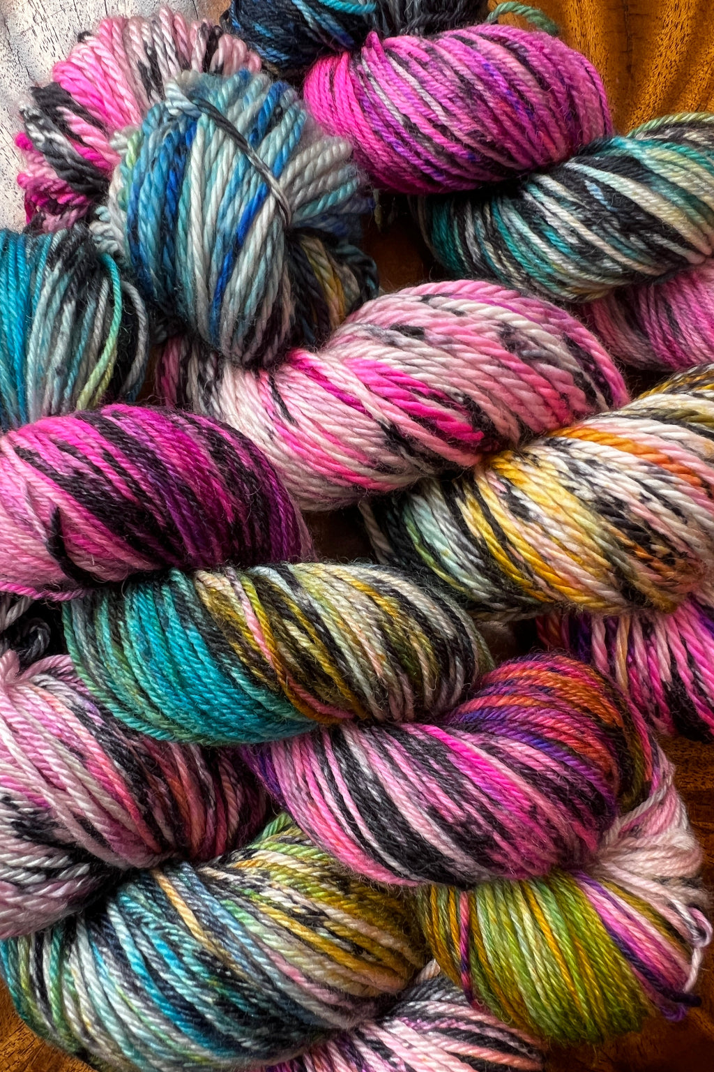 Four skeins of bright pink, purple, blue and golden merino yarn, hand dyed in Minneapolis, by Painted Skein in Birch Rainbow colorway.