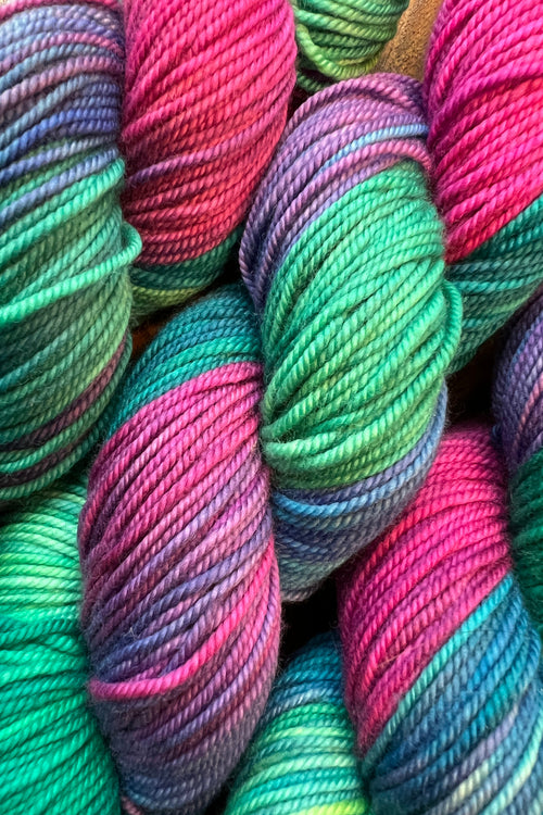 three skeins of Bohemian Rhapsody hand dyed yarn in greens, blues, purples and shocking magenta. Dyed in Minnepolis.