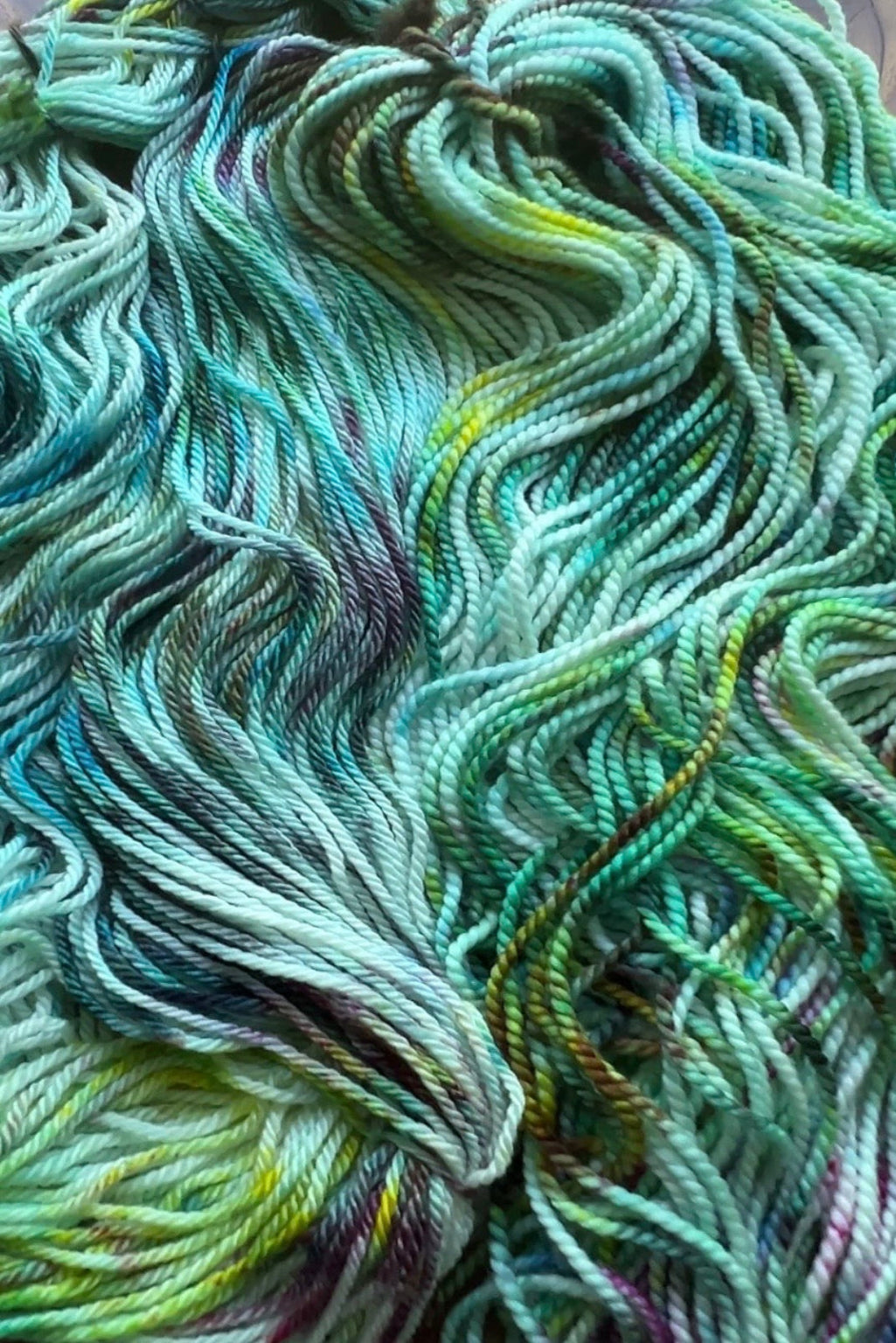 Sample skein showing the multi-tonal ocean colors and gold shimmers of Neptune’s Garden hand-dyed yarn.