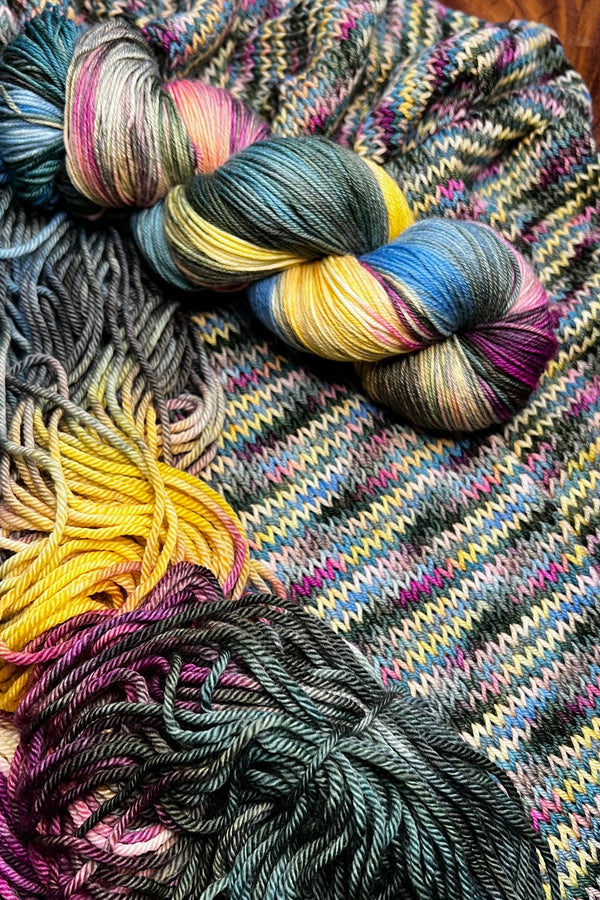 Lily Pad yarn display with skeins of yarn and knit sample. Hand dyed in Minneapolis by Painted Skein with magenta, yellow, sage, forest and brown ones.