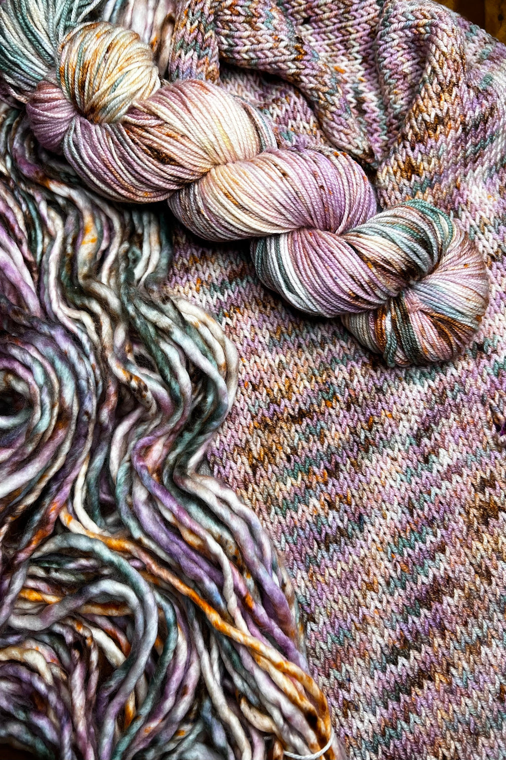 Pink Dancer yarn display with skeins of yarn and knit sample. Hand dyed in Minneapolis by Painted Skein with pink, mauve, yellow, mint, sage and brown tones.