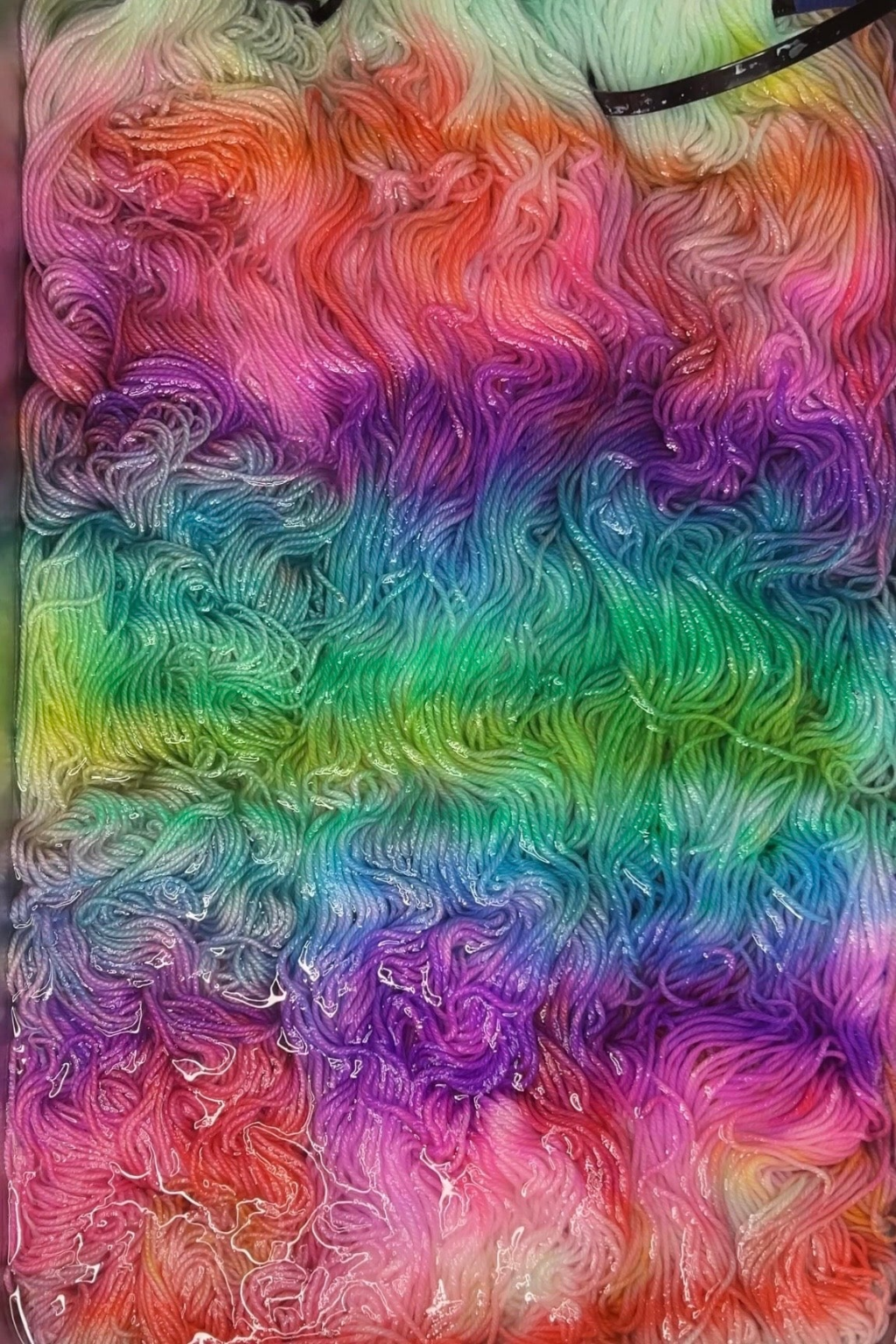 Unicorn and Rainbows yarn being dyed in Minneapolis, bright pink, purples, blues and greens swirl in pan.