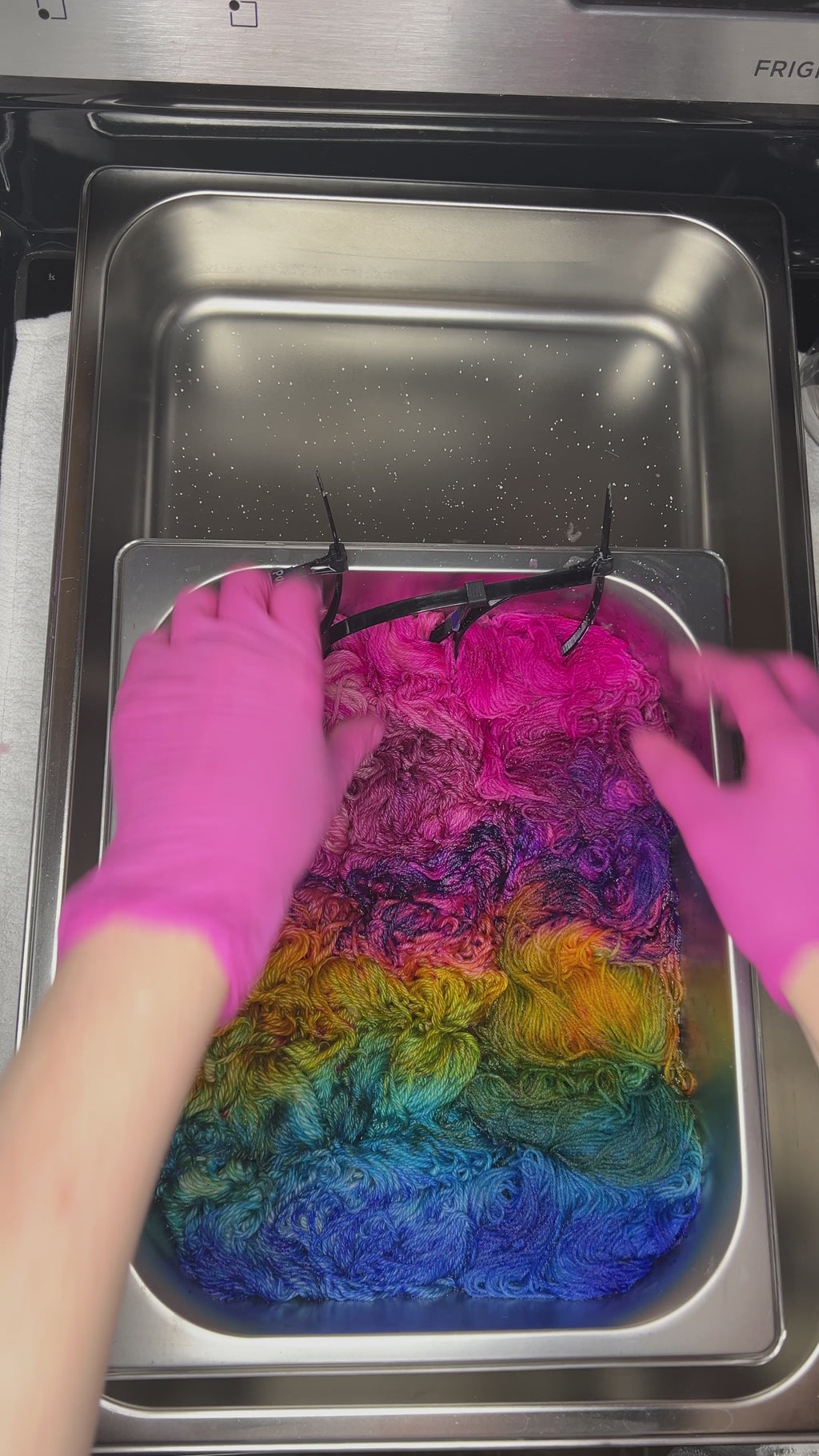 Video of wet skeins of bright pink, purple, blue and golden merino yarn, hand dyed in Minneapolis, by Painted Skein in Birch Rainbow colorway.