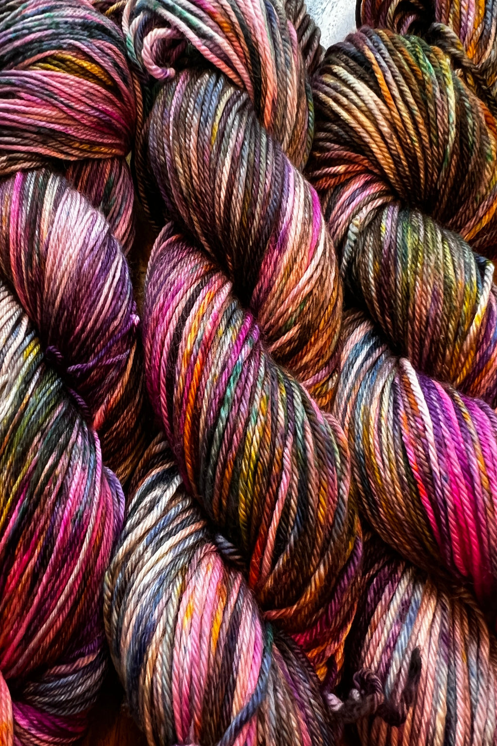 Painterly air brushed and speckled merino yarn. Hand dyed in shades of brown, hot pink, purple, lavender, golden orange, green and blue.